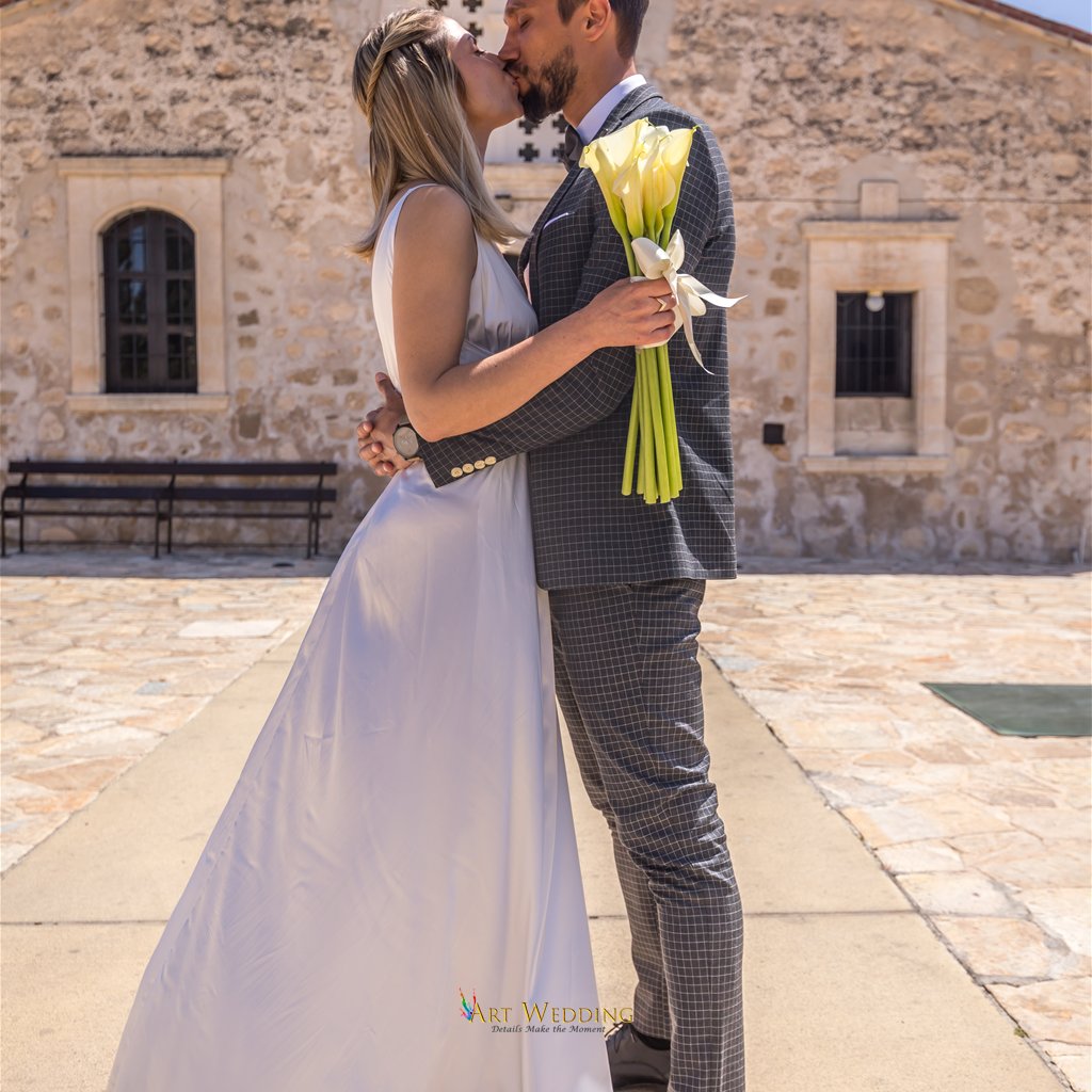 Couple kissing with a calla lily bouquet by a stone building