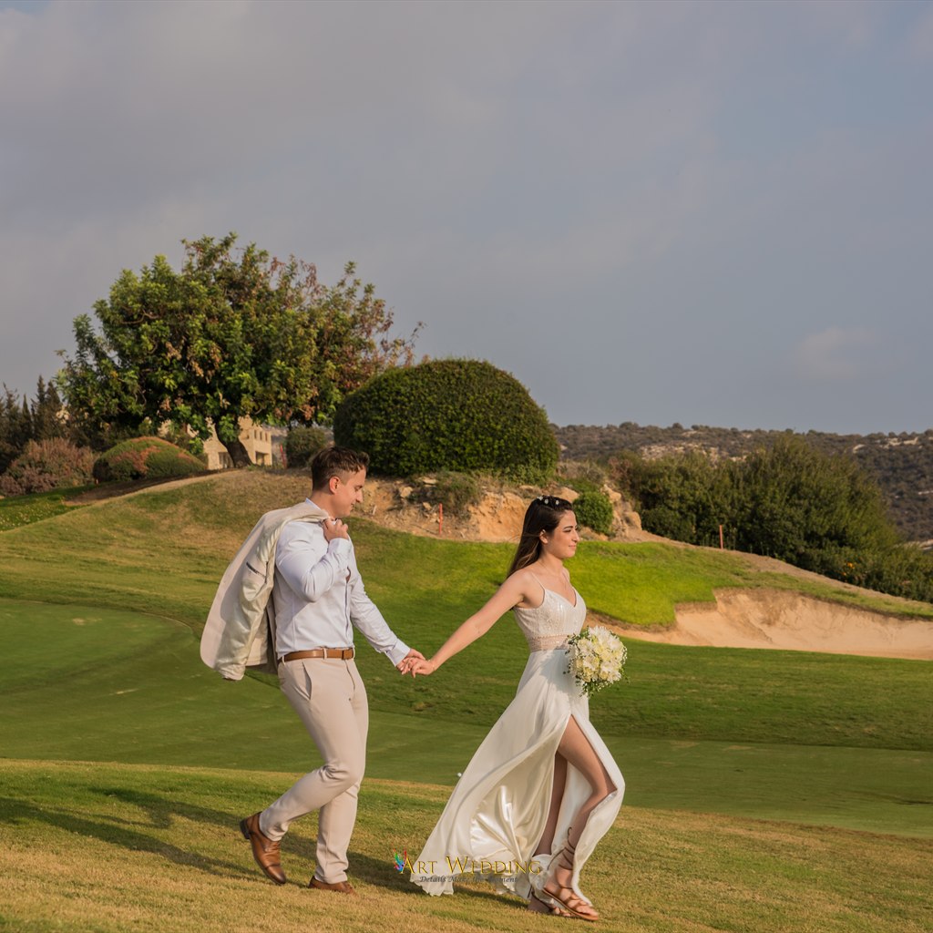 Bride and groom walking hand in hand across a green lawn