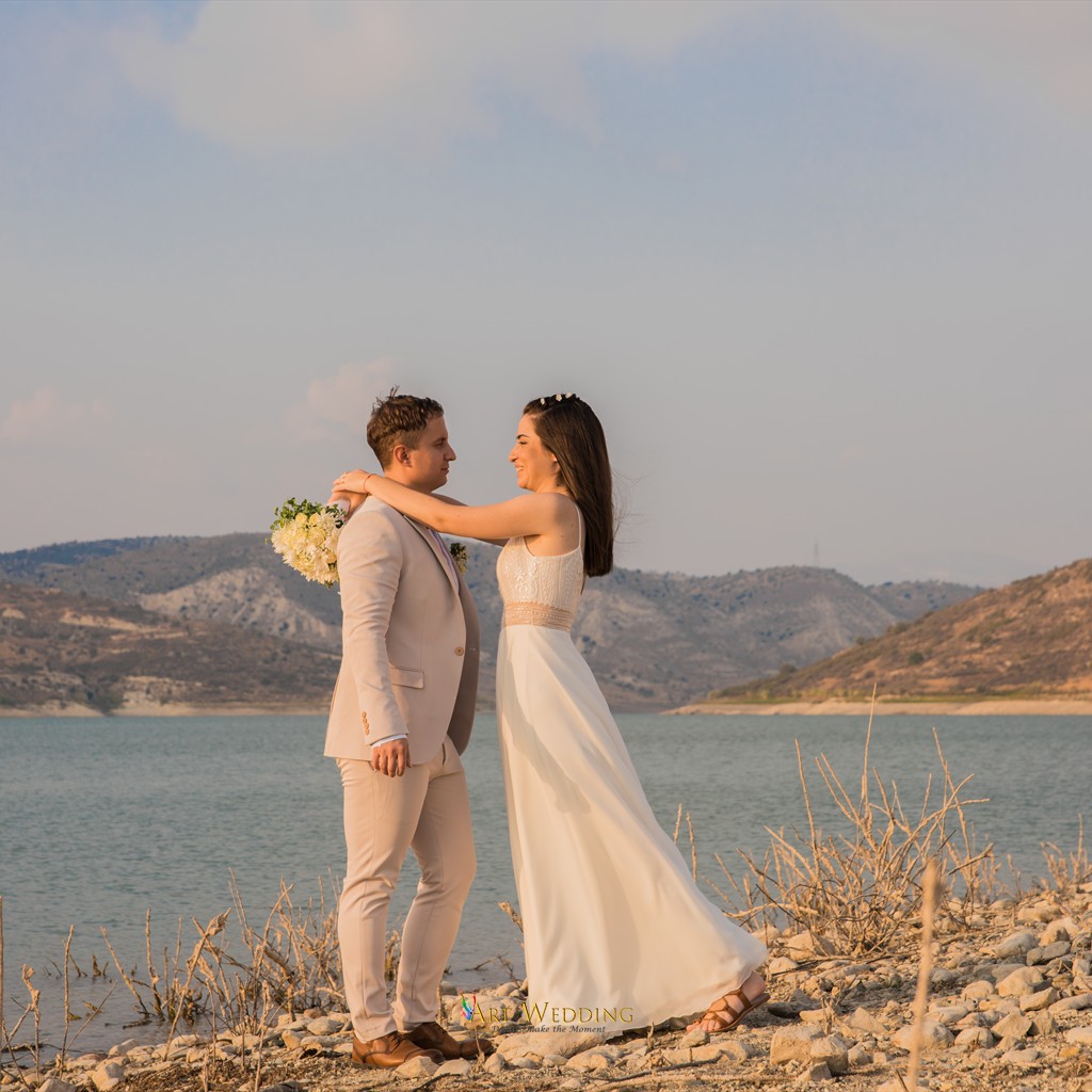 Wedding portrait by the water surrounded by hills