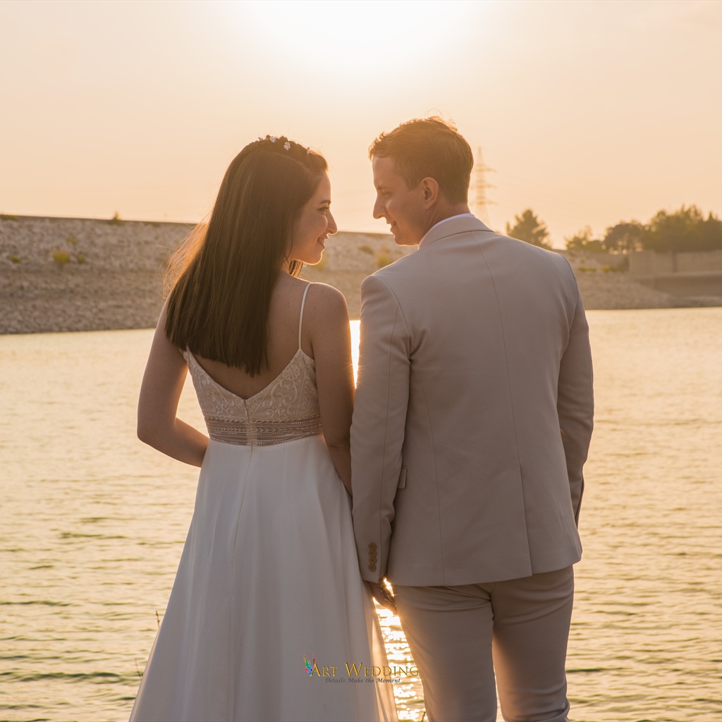 Newlyweds by the water looking at each other at sunset