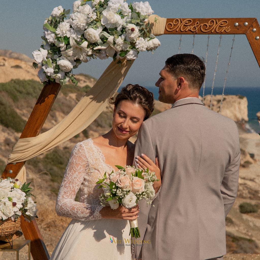 Bride embracing the groom beside a wooden wedding arch