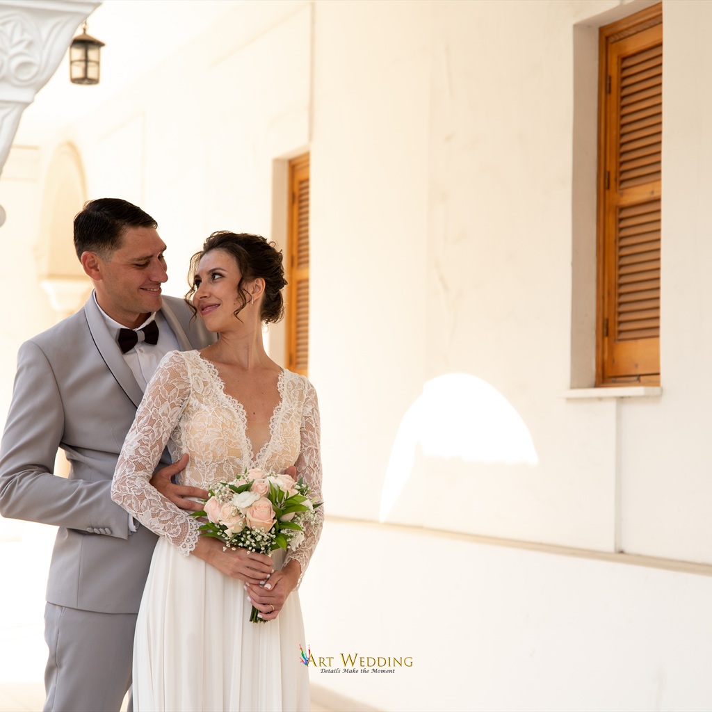 Wedding portrait by a pale wall with wooden shutters