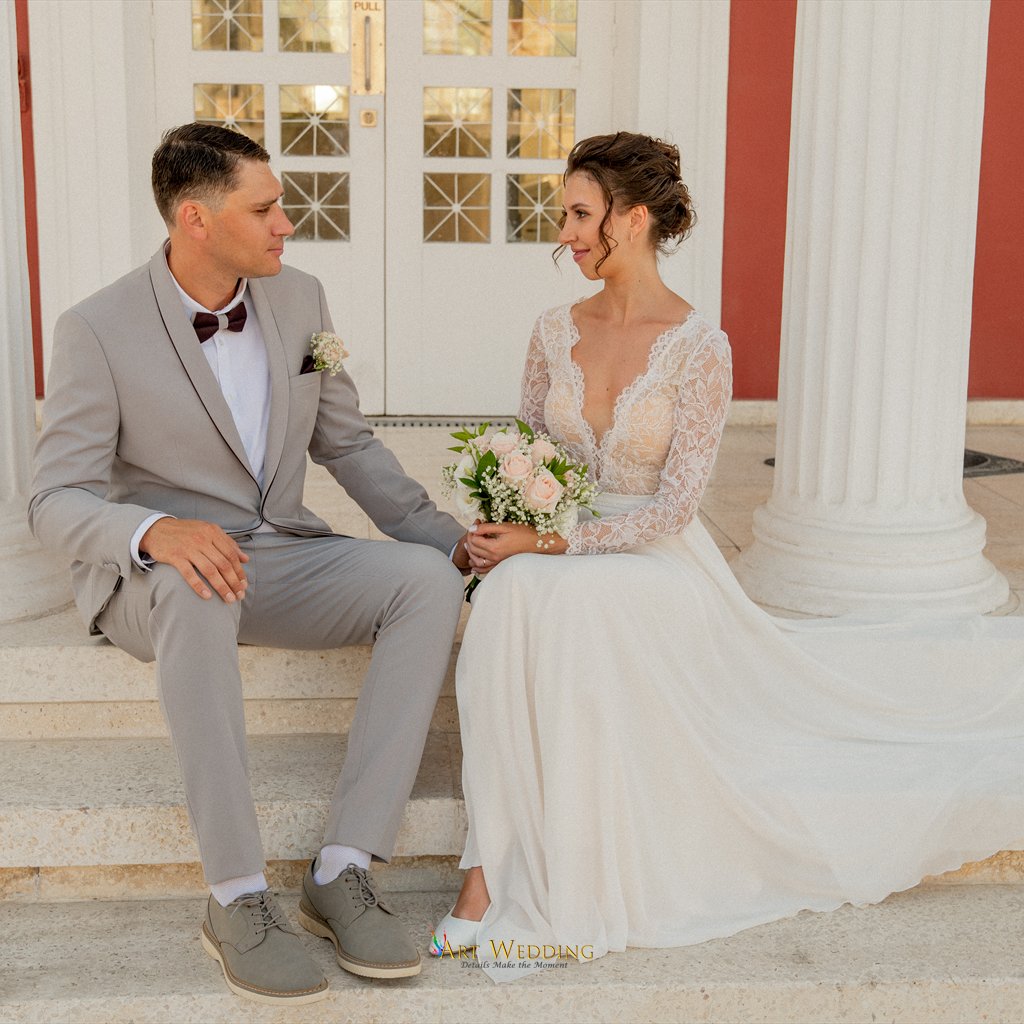 Newlyweds seated on steps between white columns