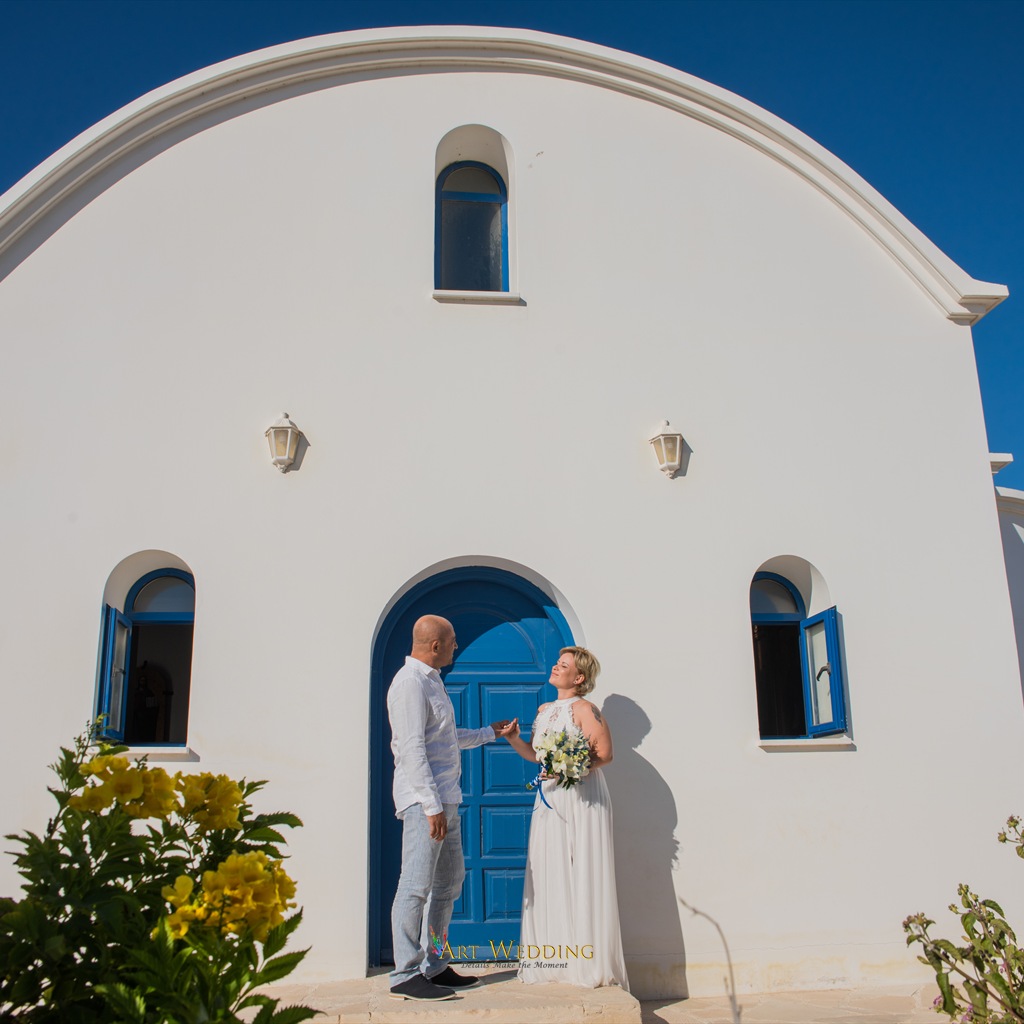 Bride and groom by the blue doors of a white church