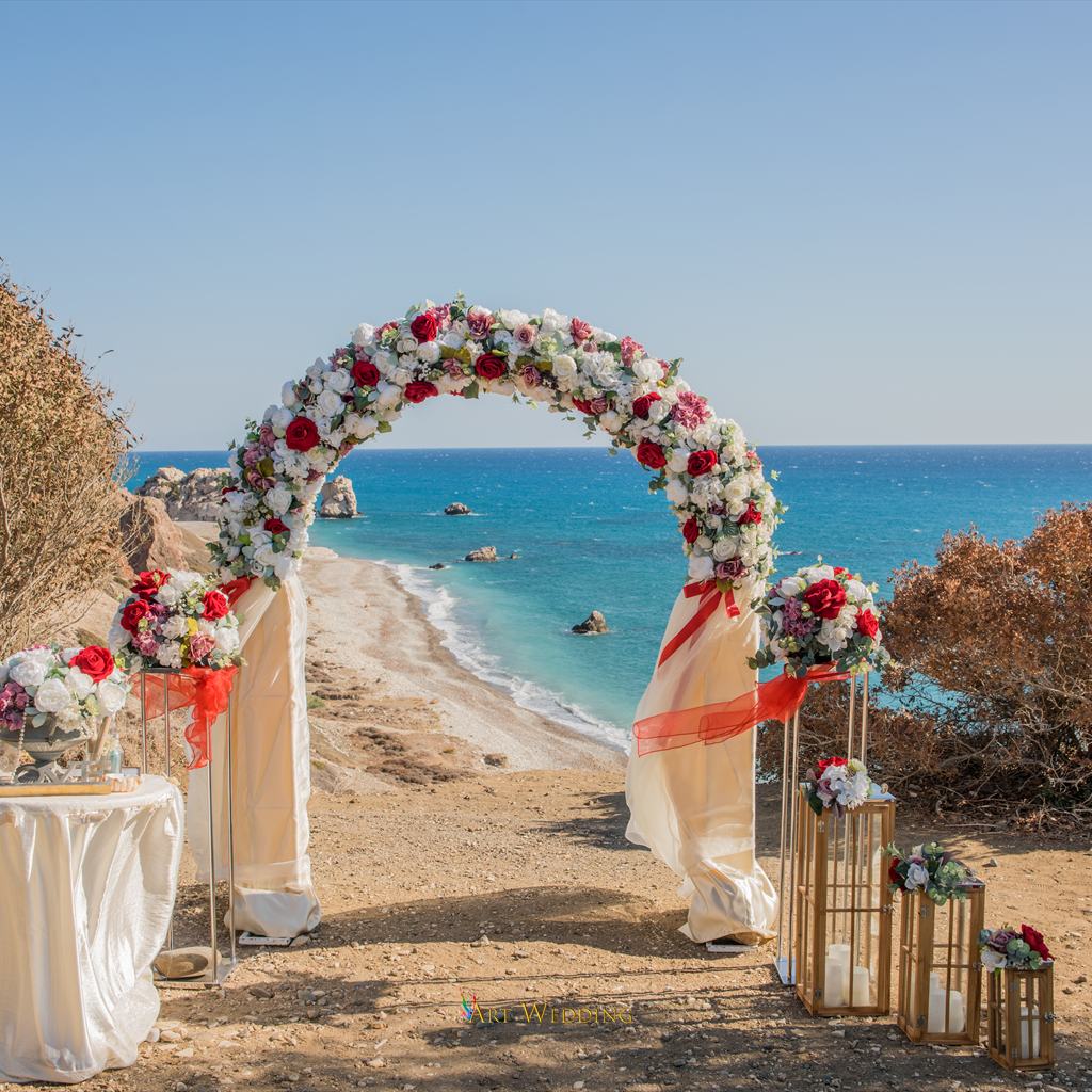 Round wedding arch with red and white flowers above the sea
