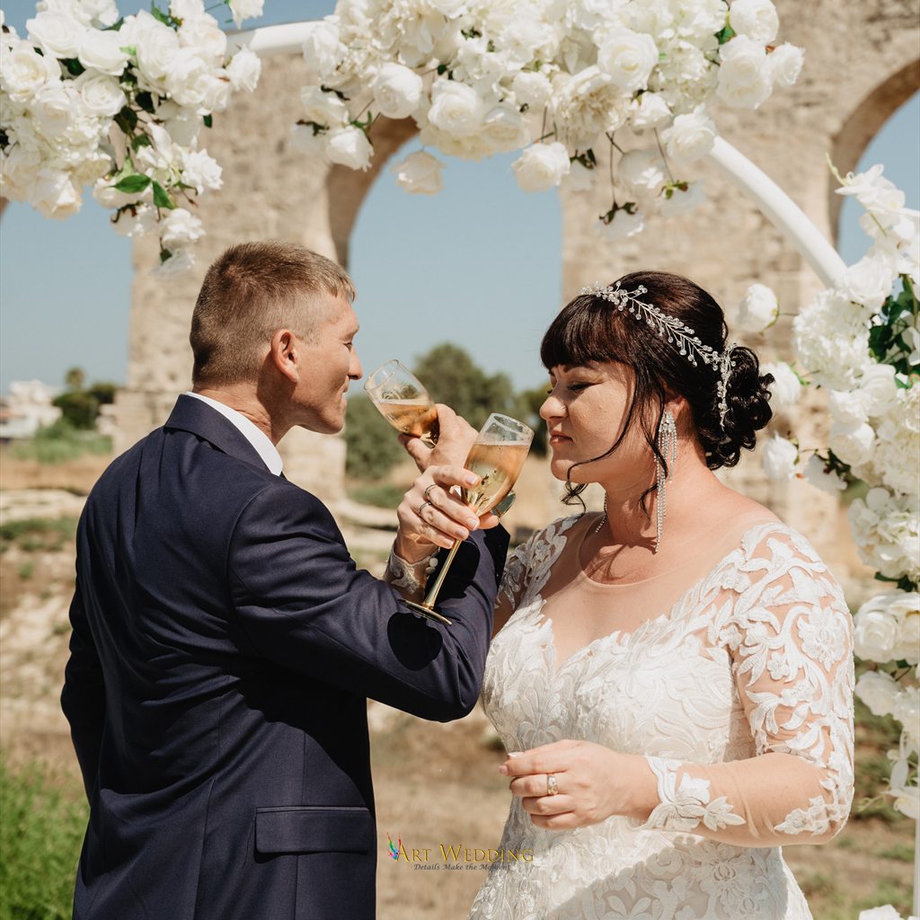 Wedding toast beneath the floral arch at Kamares