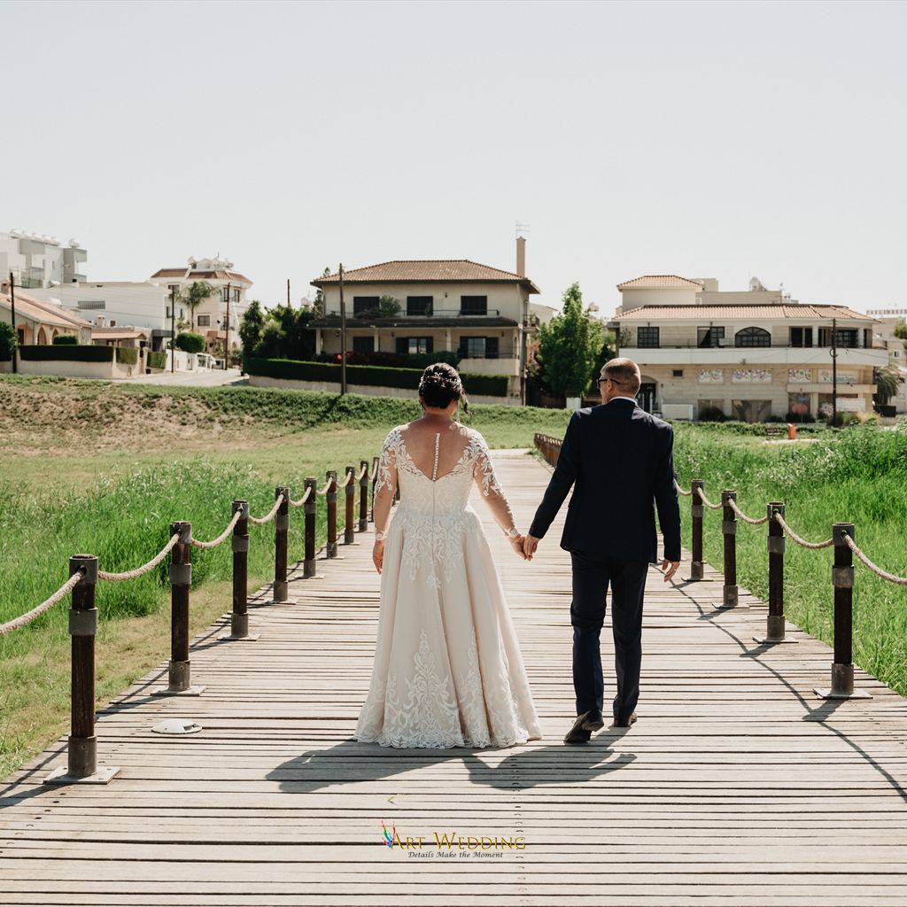 Newlyweds walking hand in hand along a wooden path