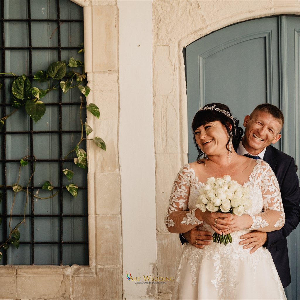 Newlyweds embracing by a blue door in Larnaca