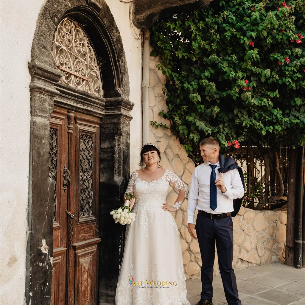 Newlyweds beside an old door and flowering bougainvillea