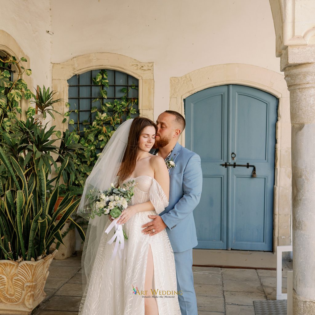 Couple with a bouquet beside a blue door in Larnaca