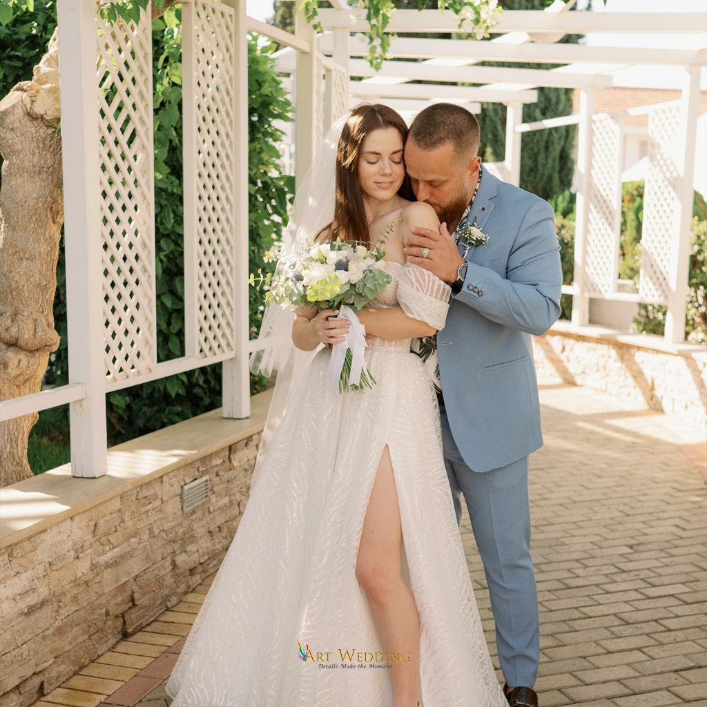 Newlyweds embracing beneath a white pergola