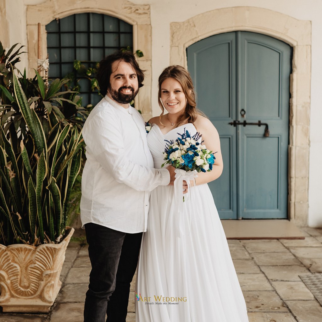 Wedding portrait by a blue door with a blue and white bouquet