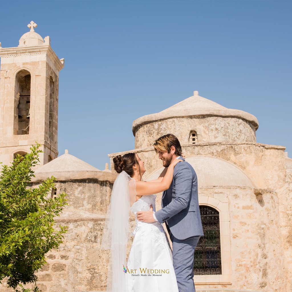 Newlyweds embracing by a stone church
