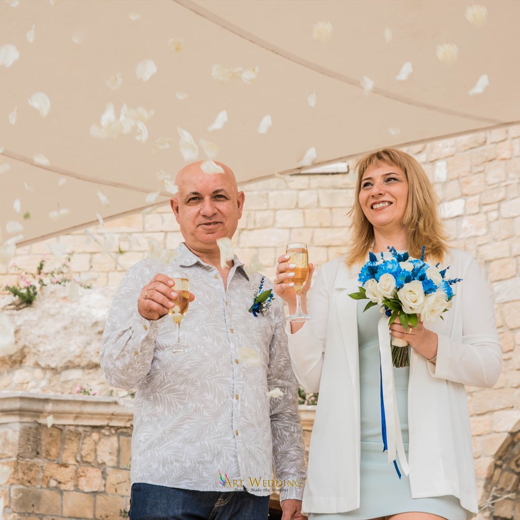 Newlyweds raising a toast beneath flower petals