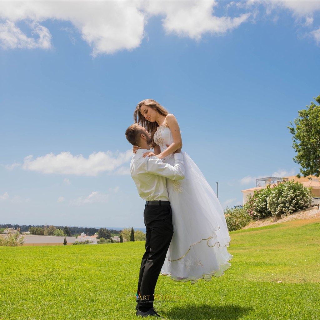Groom lifting the bride on a green lawn