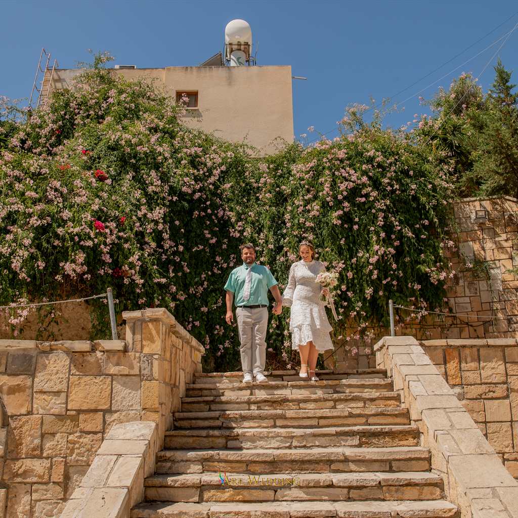 Newlyweds on stone steps surrounded by flowers