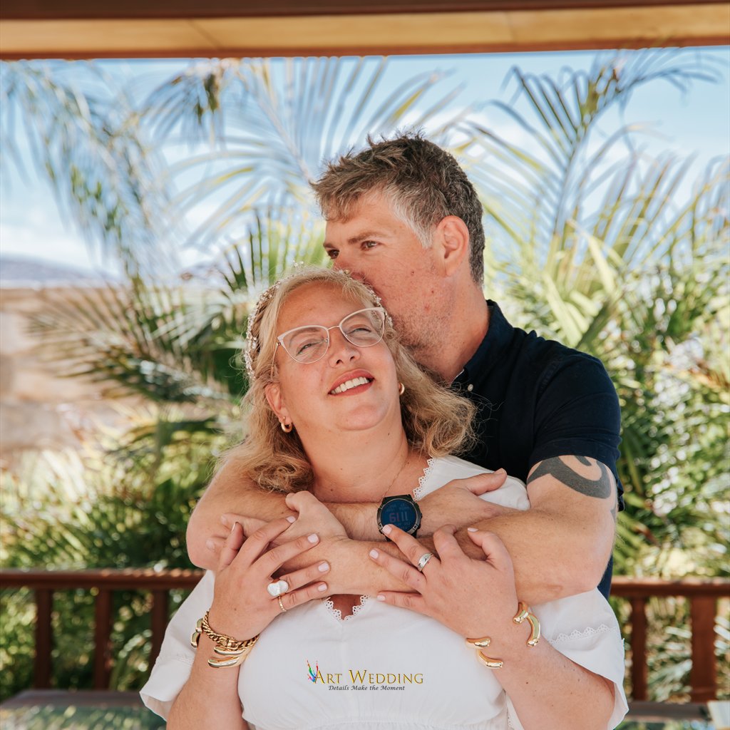 חיבוק של הזוג הטרי על רקע דקלים
