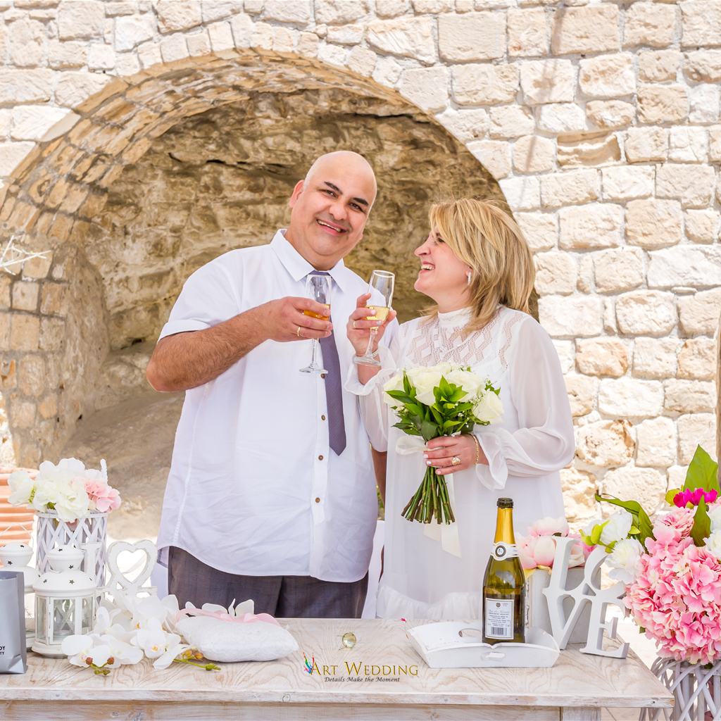 Couple raising glasses by a decorated ceremony table