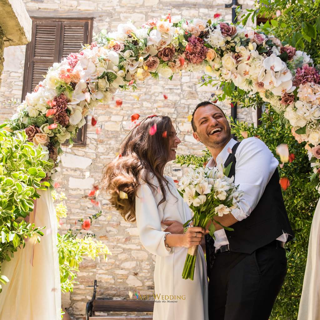 Happy newlyweds under falling flower petals — Lefkara, Cyprus