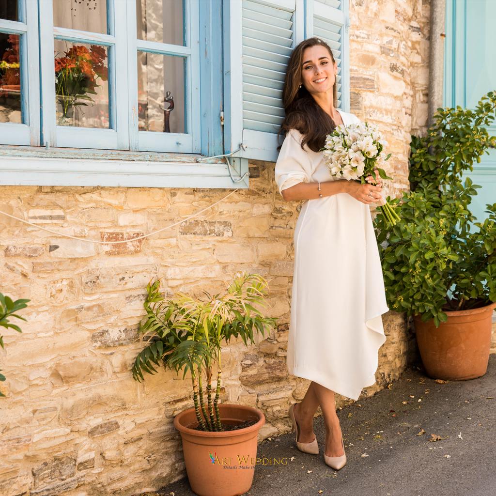 Bride with a white bouquet beside a blue window — Lefkara, Cyprus