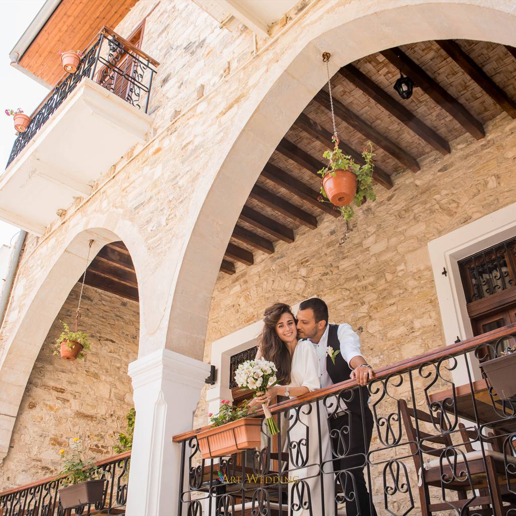 Newlyweds on a balcony beneath stone arches — Lefkara, Cyprus