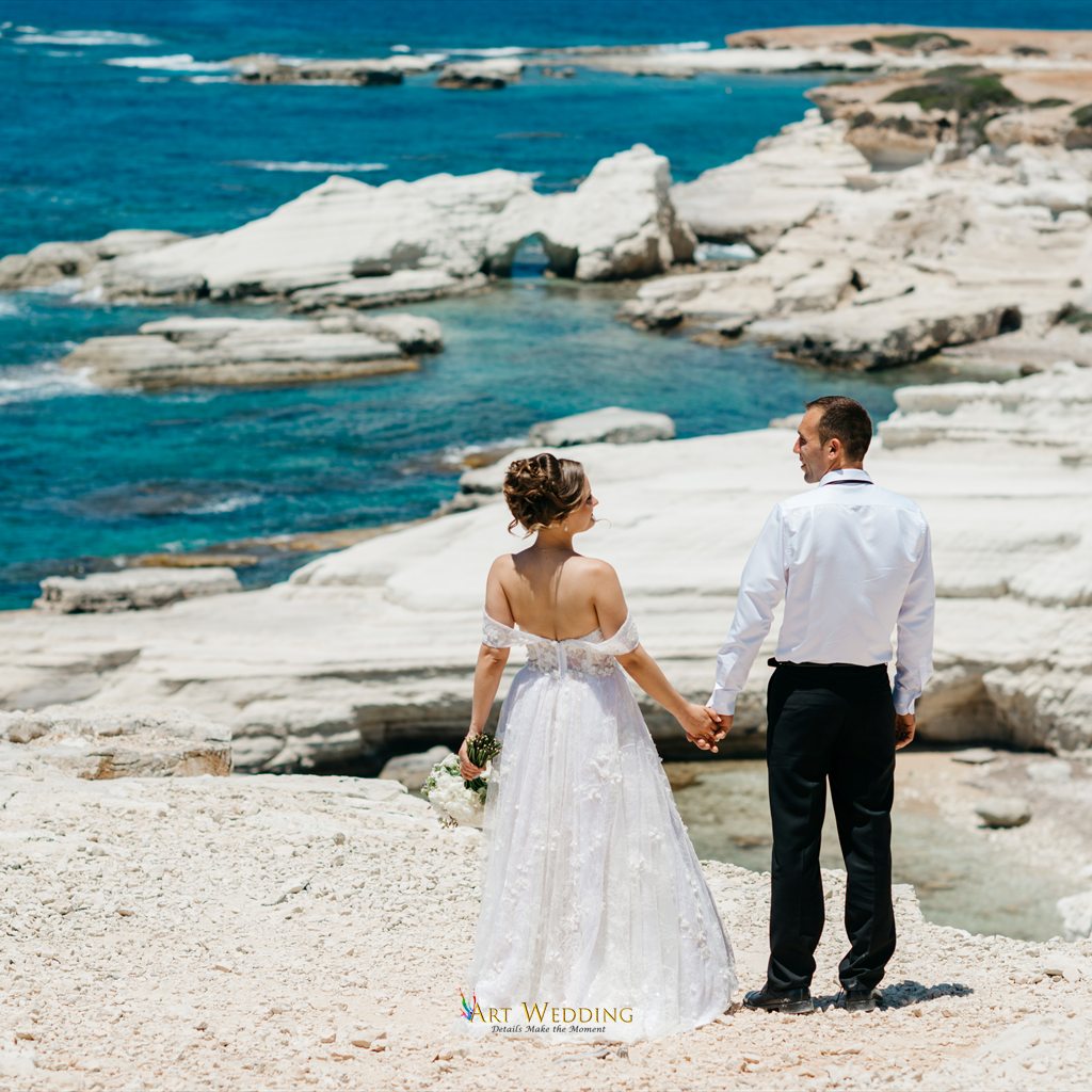 Newlyweds holding hands overlooking the sea
