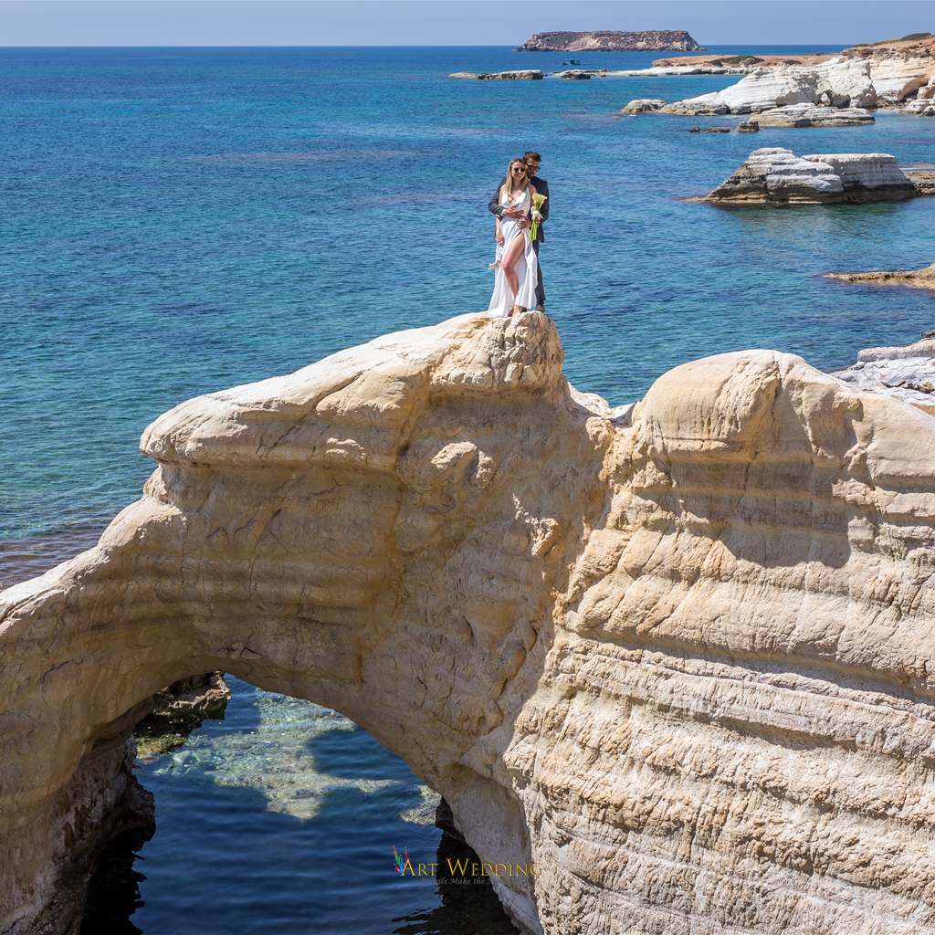 Newlyweds on a natural rock arch beside the sea
