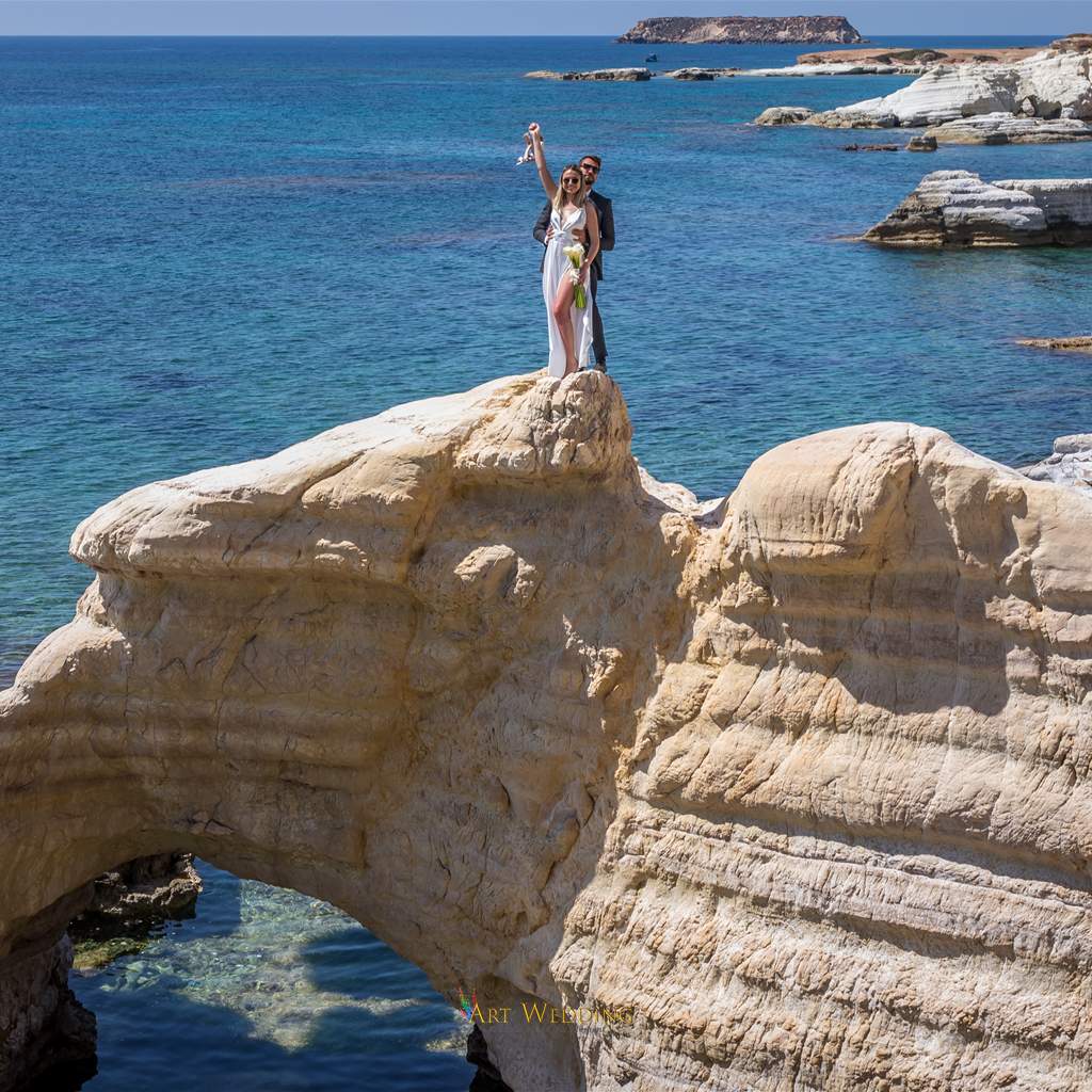 Newlyweds on a natural rock arch beside the sea