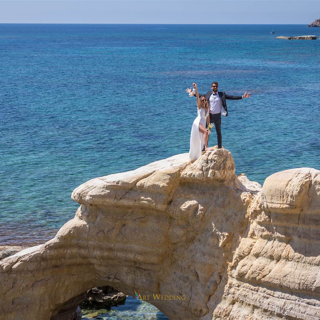 Newlyweds on a natural rock arch beside the sea