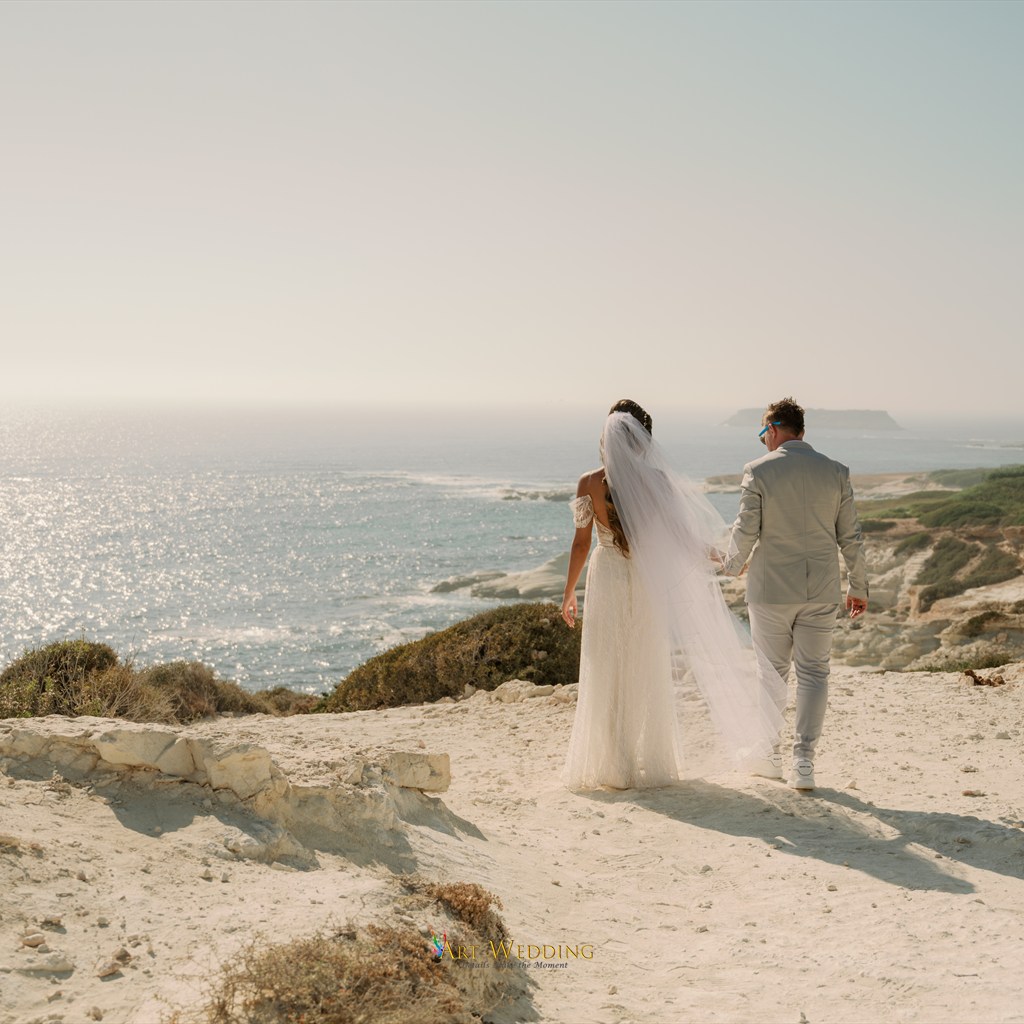 Newlyweds holding hands overlooking the sea