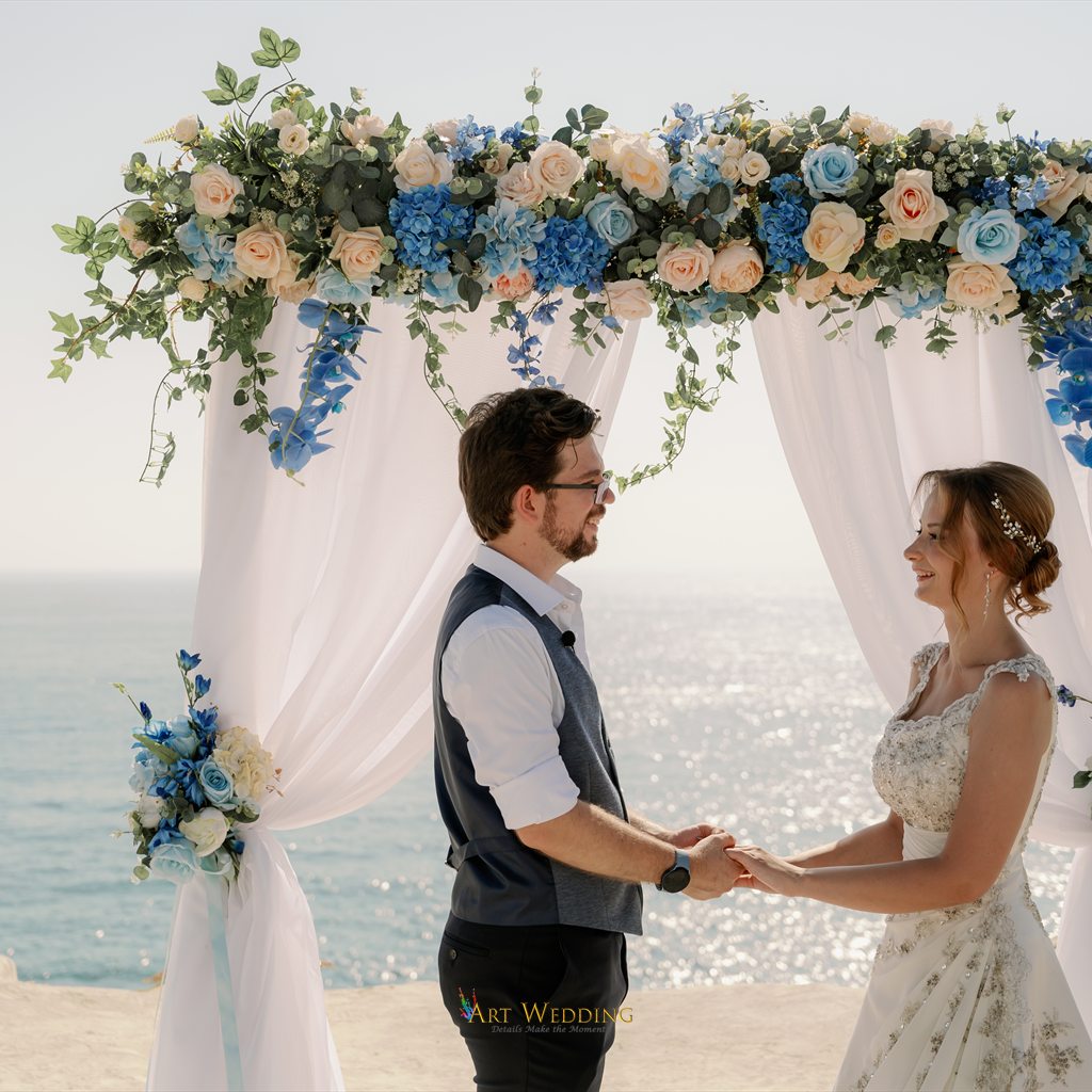 Bride and groom holding hands beneath the arch