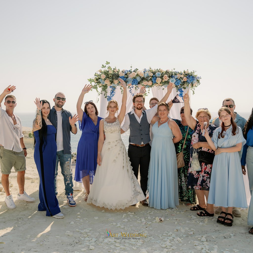 Newlyweds with family and guests beside the arch