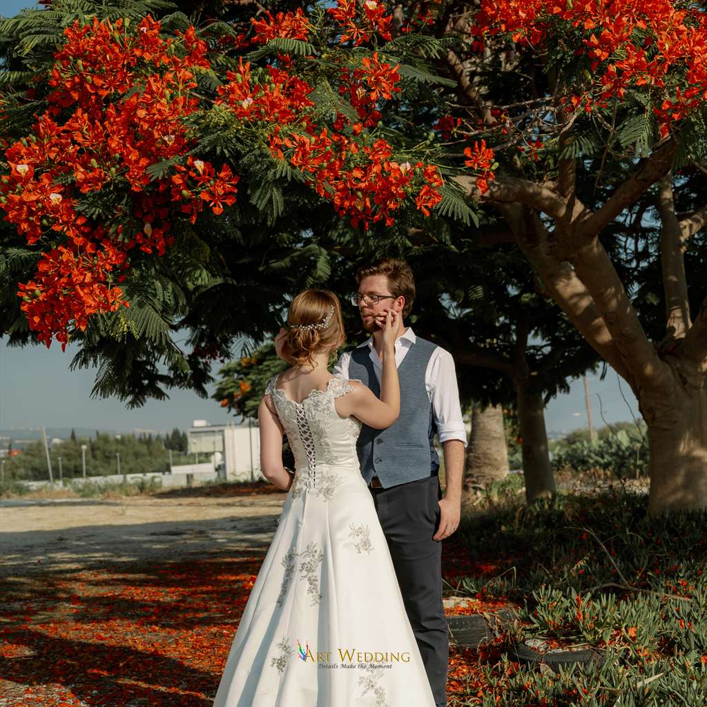Newlyweds beneath a red-flowering tree