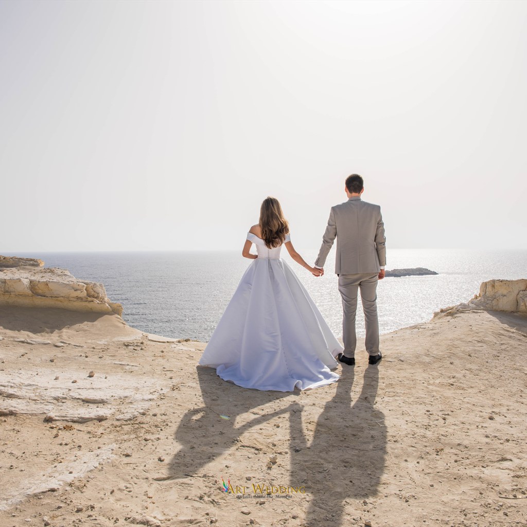 Newlyweds holding hands overlooking the sea