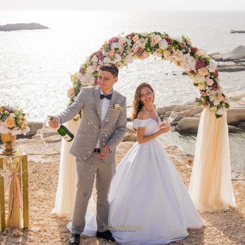 Groom opening champagne beside the bride
