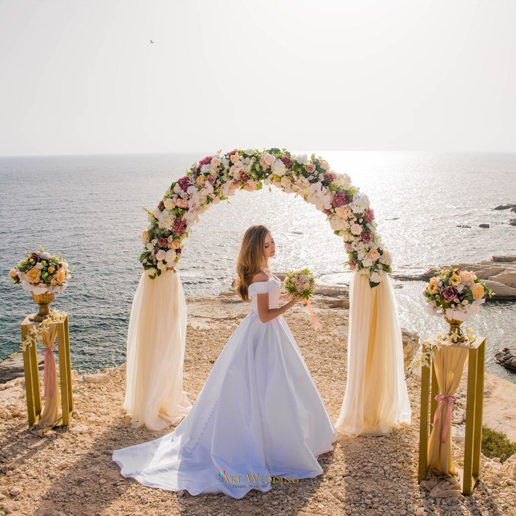 Bride beneath a floral arch by the sea