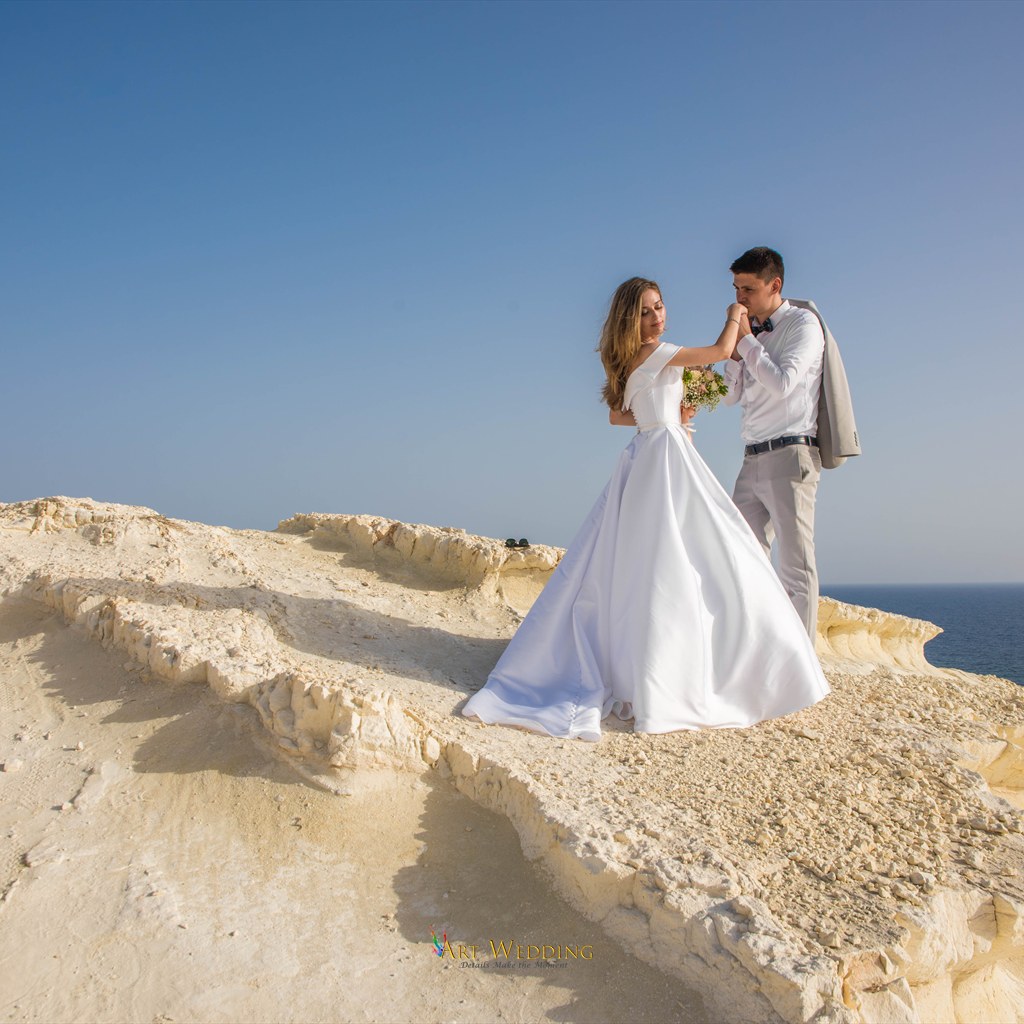 Groom kissing the bride’s hand on the white cliffs