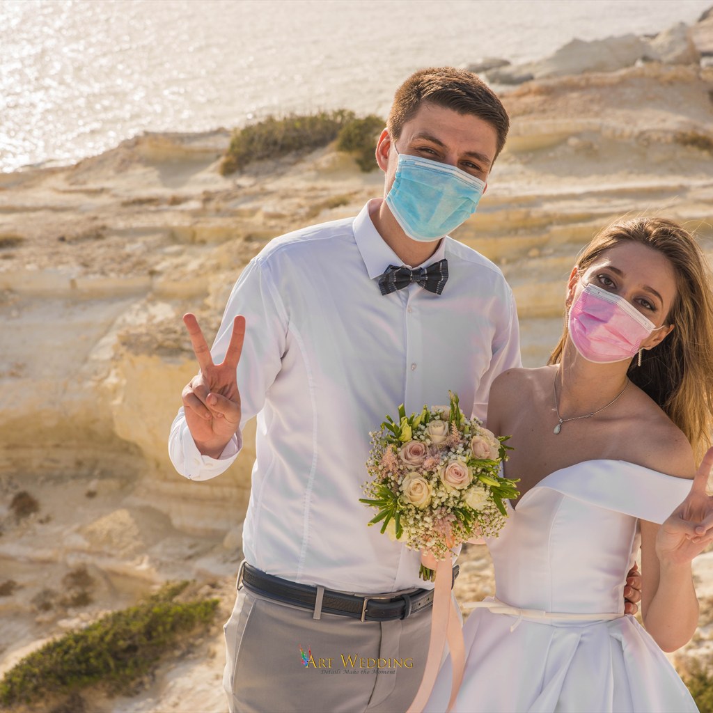 Newlyweds wearing face masks on the coast