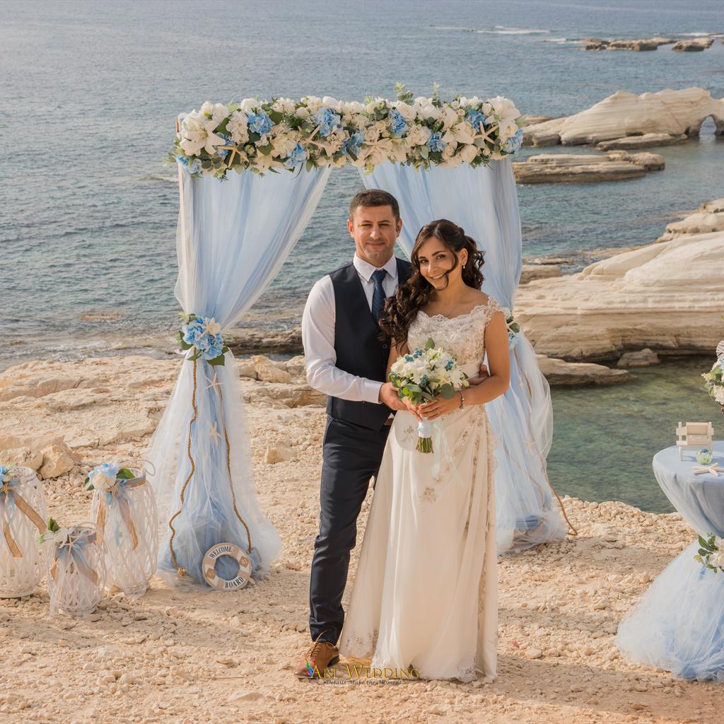 Newlyweds beneath a white and blue floral arch