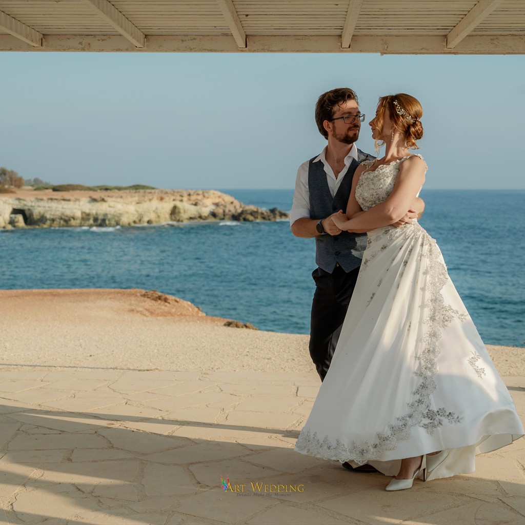 Newlyweds embrace beneath the canopy overlooking the sea