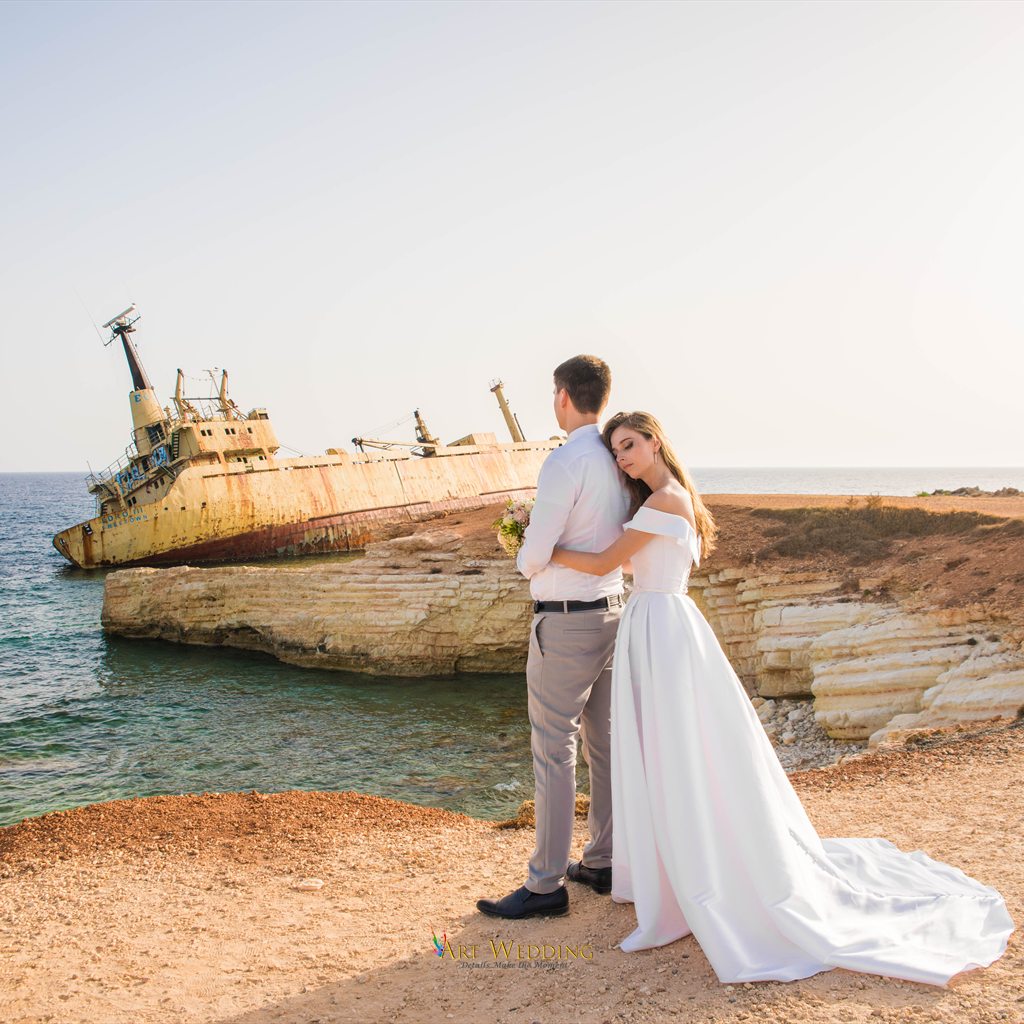 Bride embraces the groom with the shipwreck in the background