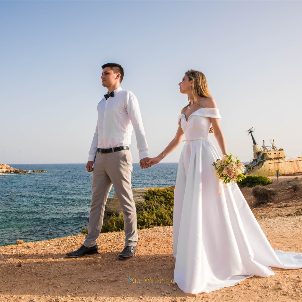 Wedding couple hold hands overlooking the shipwreck