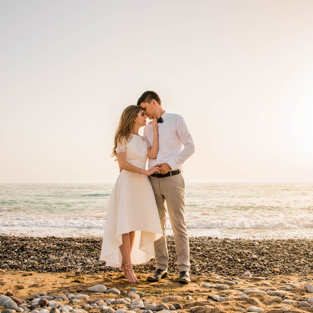 Tender portrait of newlyweds by the sea in evening light